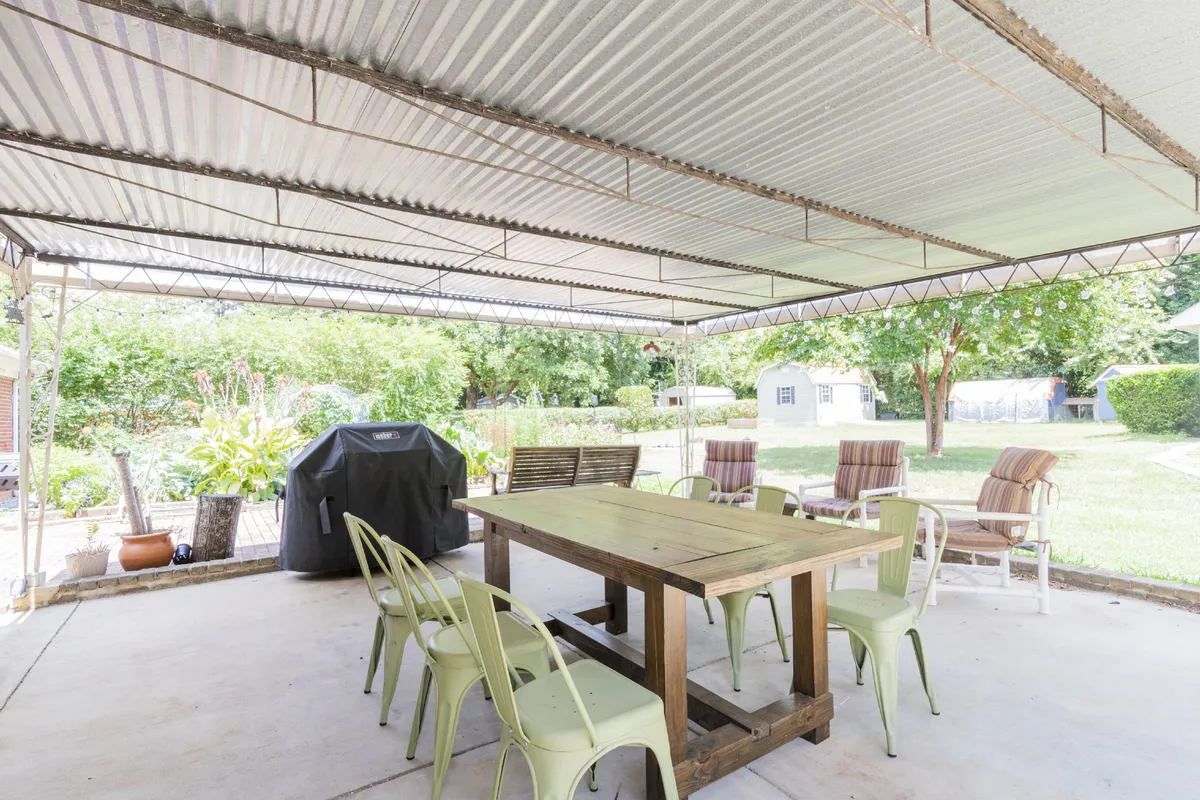 This image features a wooden dining table set on a patio, complemented by green chairs and a grill—suggesting a space designed for alfresco dining and social gatherings. The ambiance is casual and inviting, ideal for families and friends to enjoy meals outdoors.