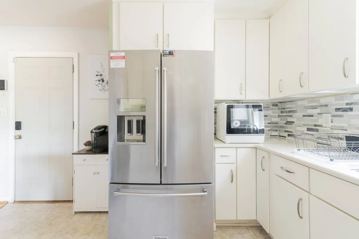 This image features a modern kitchen with a sleek stainless steel refrigerator, a clean countertop, and a microwave. The space is inviting and well organized, suggesting it's ideal for preparing home-cooked meals and accommodating daily routines.
