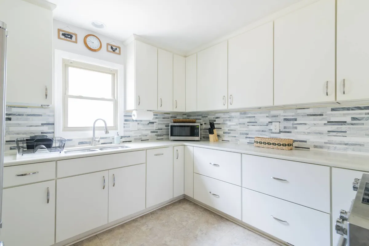 A view of kitchen countertops with modern appliances, a decorative backsplash, and a window providing natural light. The space looks functional, clean, and ready for both casual and elaborate cooking.