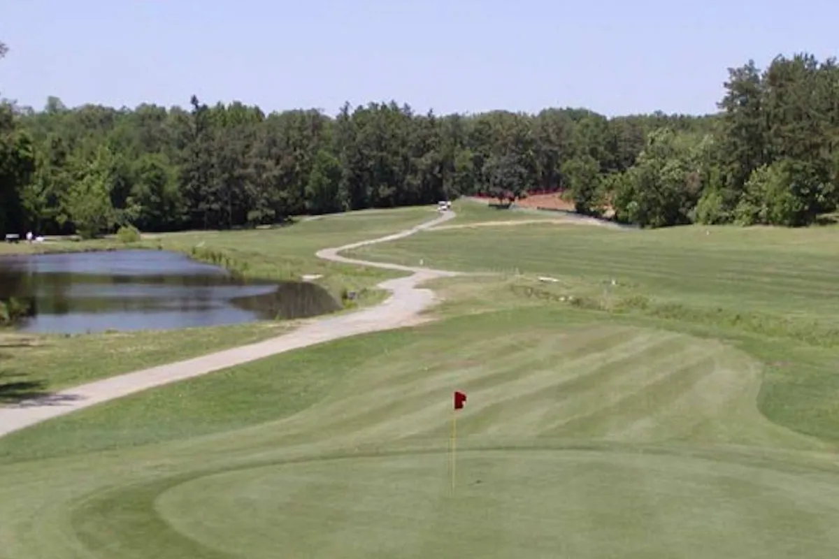 A lush golf course with a pond, winding pathway, and plenty of greenery sets a tranquil and recreational tone. The scene captures a relaxed afternoon on the course, with space for walking, picnicking, or simply enjoying nature together as a family.