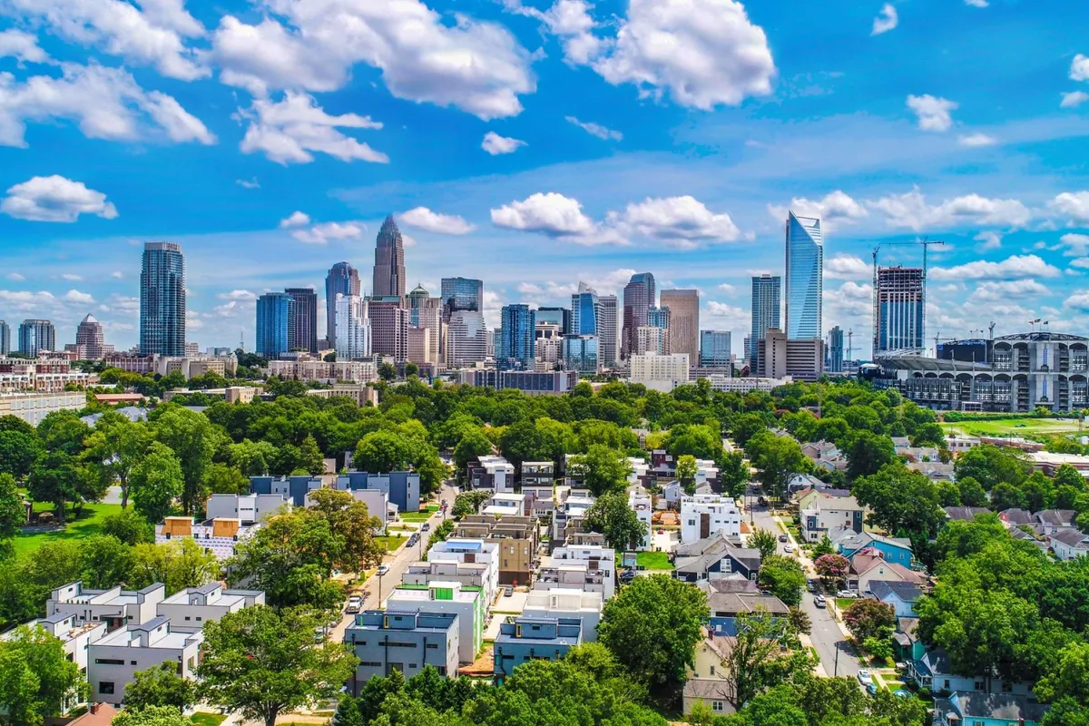 This image captures a sweeping city skyline in the background, with lush green parks and residential neighborhoods in the foreground. The urban setting is dynamic, offering a glimpse into both the energetic city life and accessible nature, reflecting local amenities and community environment.