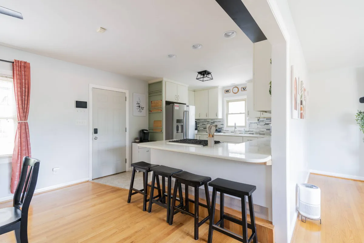 An open kitchen scene featuring a kitchen island with bar stools and a window with curtains. The layout encourages both cooking and socializing, making it easy for families or groups to gather and share meals.